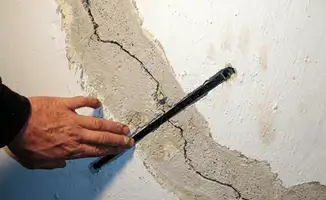 A wall with a large crack is being inspected by a professional in Tucson, AZ